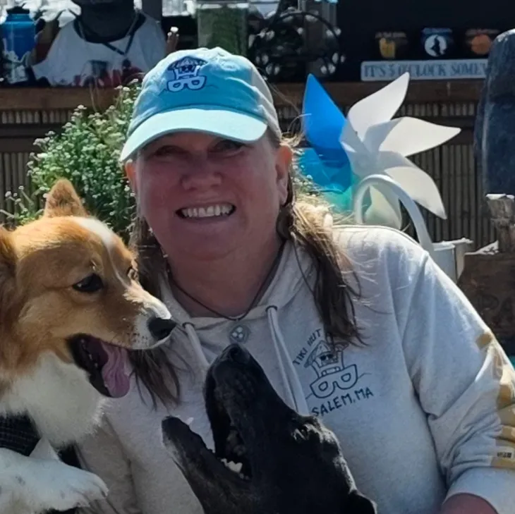 Woman in cap smiling with two dogs