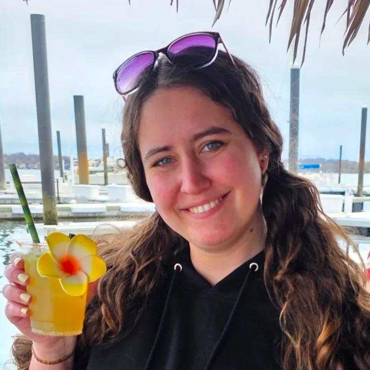 Smiling woman holding tropical drink at marina