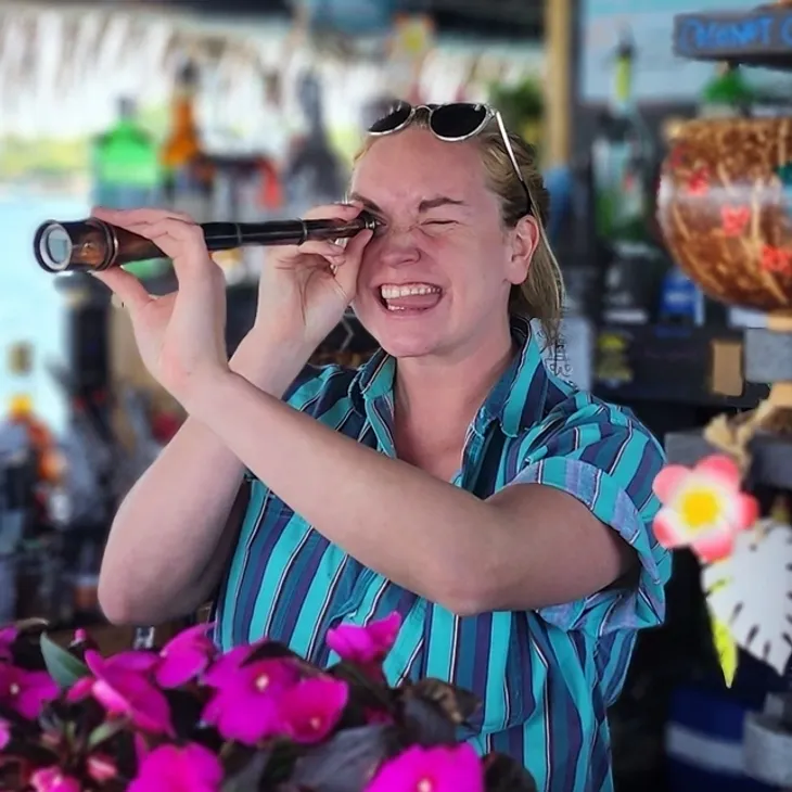 Smiling woman looking through handheld telescope