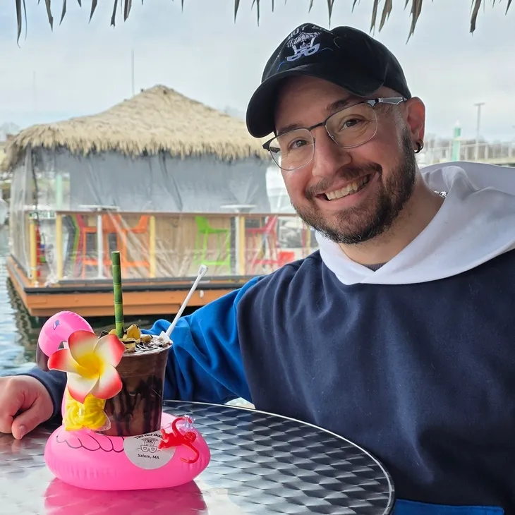 Smiling man with tropical drink at tiki bar
